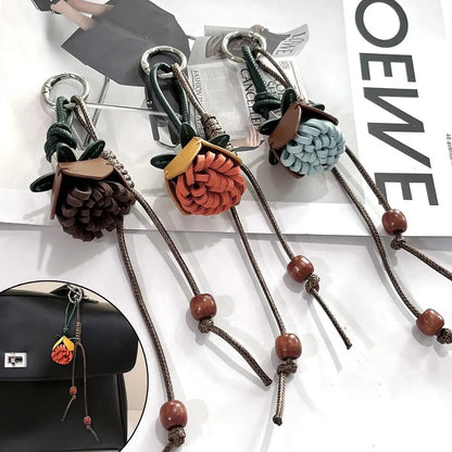Breloque de sac à main avec pompon fleuri pour femme, porte-clés haut de gamme en cuir PU, pendentif en corde tressée avec pomme de pin et fleur.