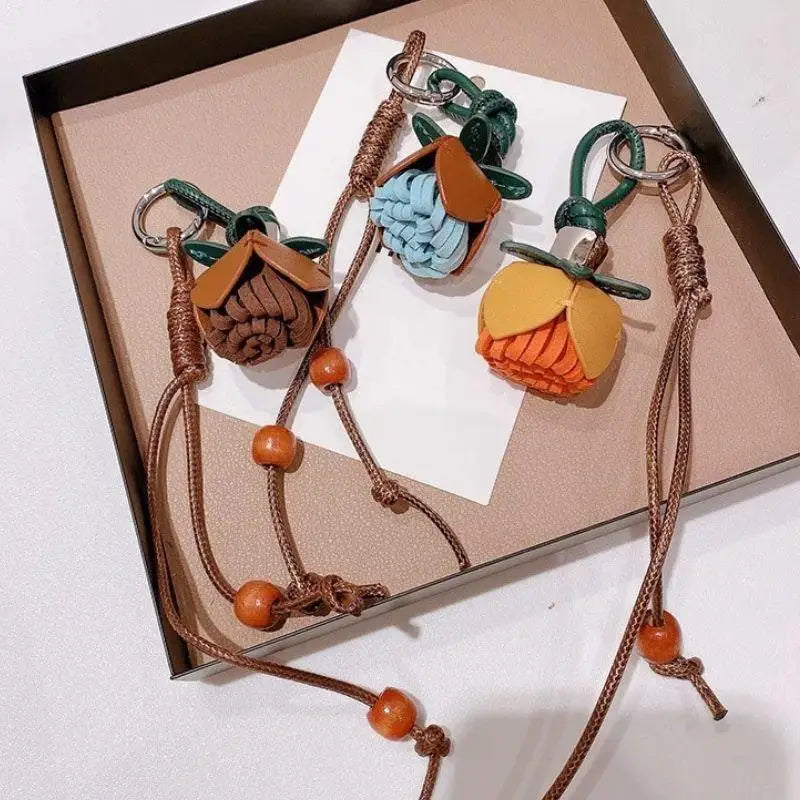 Breloque de sac à main avec pompon fleuri pour femme, porte-clés haut de gamme en cuir PU, pendentif en corde tressée avec pomme de pin et fleur.